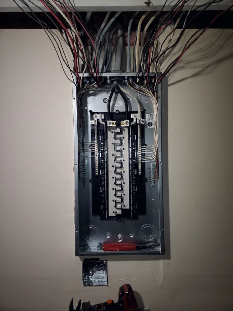 A new breaker panel with its circuits dressed down a finished wall